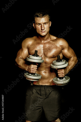 Young attractive sportsman with dumbbells. Male athletic body.