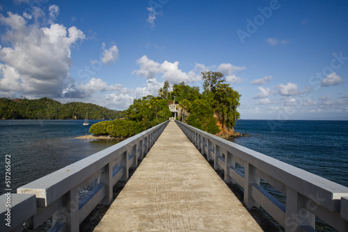 bridge over the sea to a small green tropical island, blue sky with clouds