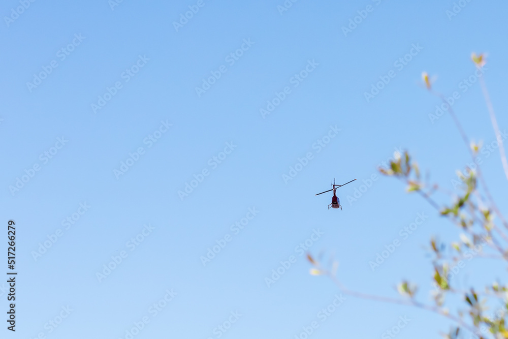 A helicopter resembling a dragonfly flies through the air in the blue sky. Air patrol. Helicopter rides A helicopter resembling a dragonfly flies through the air in the blue sky. Air patrol. Helicopter rides