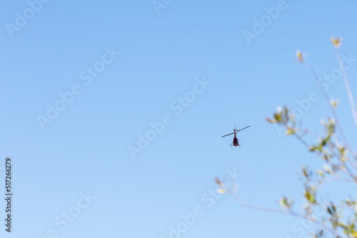A helicopter resembling a dragonfly flies through the air in the blue sky. Air patrol. Helicopter rides