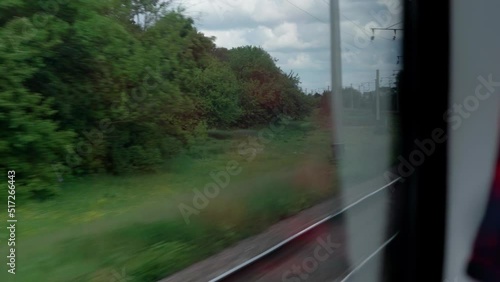 side view of high-speed turning train on landscape of beautiful nature wild field and mountains forest on cloudy sunny day in summer background. Transport, travel, railway, communication concept