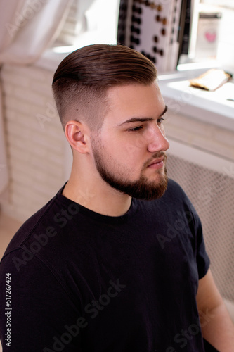 Brunette man with stylish haircut on barbershop background