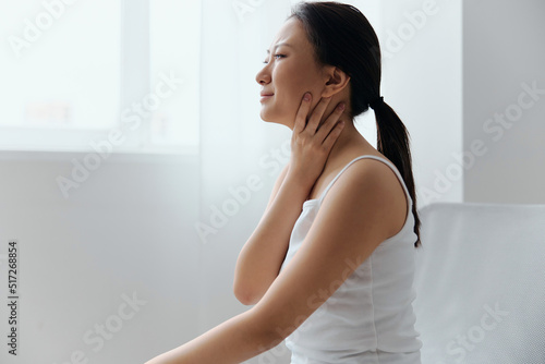 Tickling Cough. Side view of suffering crying tanned beautiful young Asian woman touch neck sore throat at home interior living room. Injuries Poor health Illness concept. Cool offer Banner