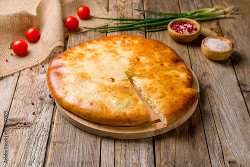 Ossetian pie with cheese on old wooden table