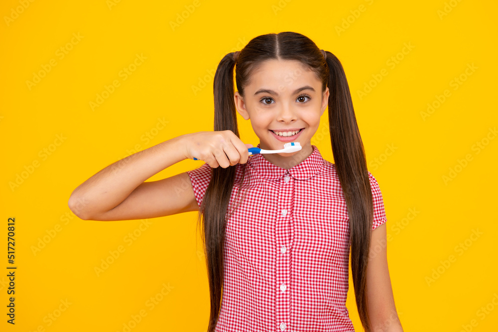 Teenager girl brushing her teeth over isolated yellow background. Daily hygiene teen child hold toothbrush, morning routine. Dental health oral care. Happy teenager, positive and smiling. Teenager girl brushing her teeth over isolated yellow background. Daily hygiene teen child hold toothbrush, morning routine. Dental health oral care. Happy teenager, positive and smiling.