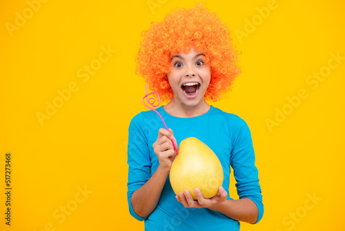 Portrait of teen child girl hold citrus fruit pummelo or pomelo  big grapefruit isolated on yellow background. Excited teenager  glad amazed and overjoyed emotions.