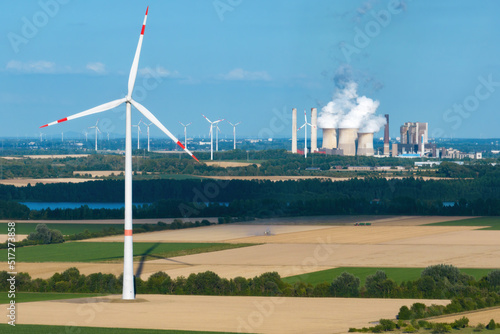 Aerial view of a wind farm with a coal-fired power plant in the background