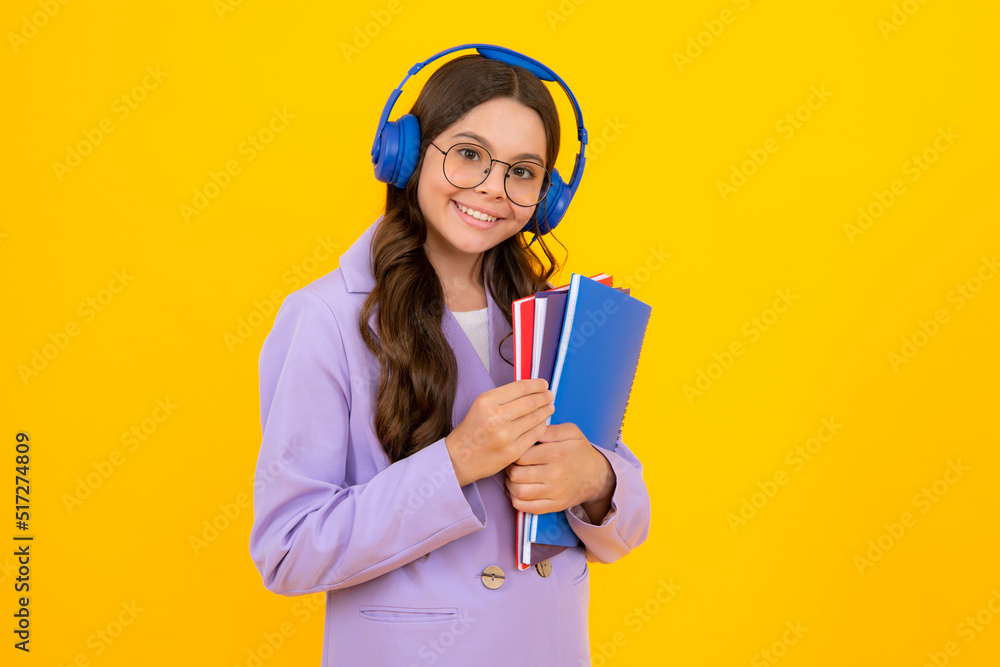 School child girl with headphones and book isoalted on yellow background. School child girl with headphones and book isoalted on yellow background.