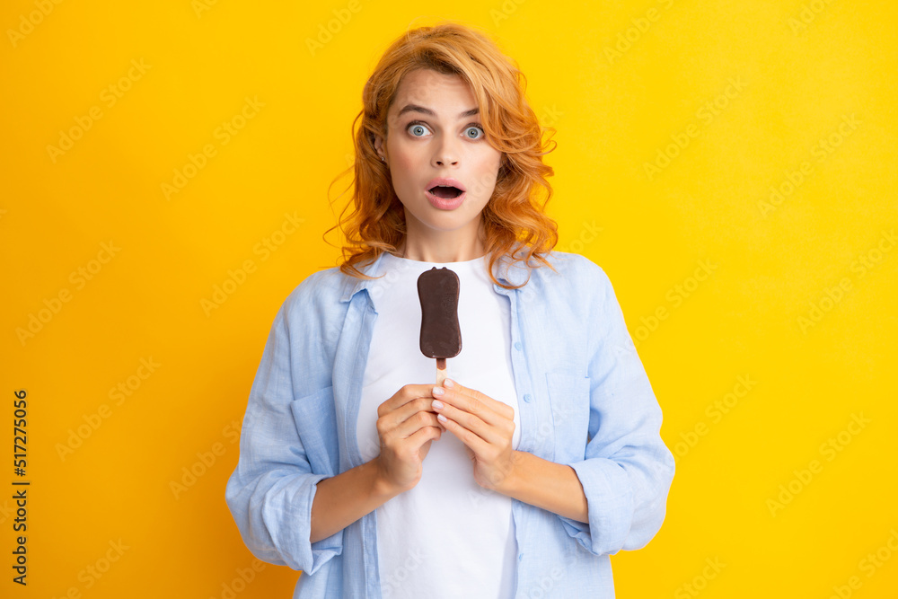 Portrait of beautiful woman eating ice cream on orange yellow background. Girl eating popsicle ice pop. Excited expression female portrait. Amazed surprised woman face. Portrait of beautiful woman eating ice cream on orange yellow background. Girl eating popsicle ice pop. Excited expression female portrait. Amazed surprised woman face.
