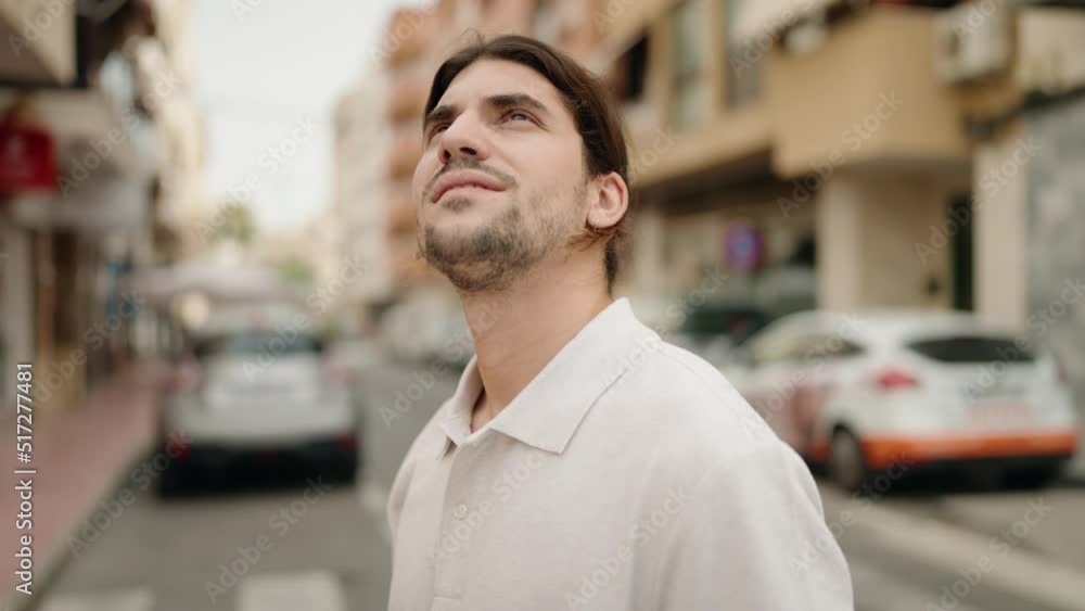 Young hispanic man looking to the sky with relaxed expression at street Young hispanic man looking to the sky with relaxed expression at street