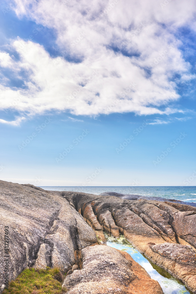 A rocky shore and a seascape view of the ocean with blue sky copy space and a mountain in the background in Camps Bay, Cape Town, South Africa. Calm, serene, tranquil beach and nature scenery A rocky shore and a seascape view of the ocean with blue sky copy space and a mountain in the background in Camps Bay, Cape Town, South Africa. Calm, serene, tranquil beach and nature scenery
