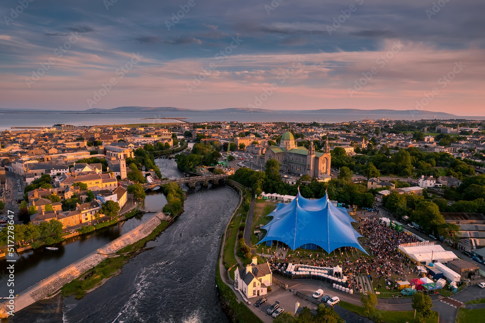 Obraz premium Aerial view on river Corrib and blue concert performance tent. Dusk sunset time. Popular town event. Tourism and travel and entertainment industry. Galway, Ireland.
