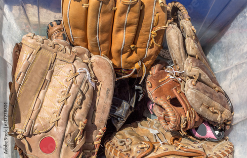 Photography Bin of  old worn baseball gloves at a team practice