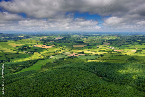 Aerial view on hills with green grass fields and forests in county Tipperary, Ireland. Emerald island nature. Irish landscape. Blue cloudy sky. Devils bit area. © mark_gusev