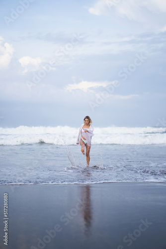 A young woman walks along the ocean at dawn, a time of meditation and reflection.