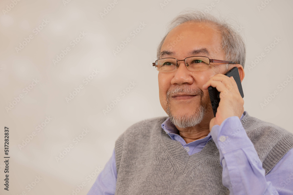 Elderly Asian man standing and play smartphone in living room with relaxing day. Elderly Asian man standing and play smartphone in living room with relaxing day.