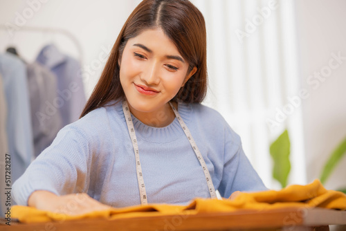 Asian woman designer checks the neatness of a brown shirt after sewing. or completed repairs photo