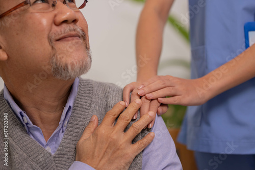 Close up hand of hands of nursing aide holding and patting winkled hand of a patient.Domiciliary care for sick elderly.