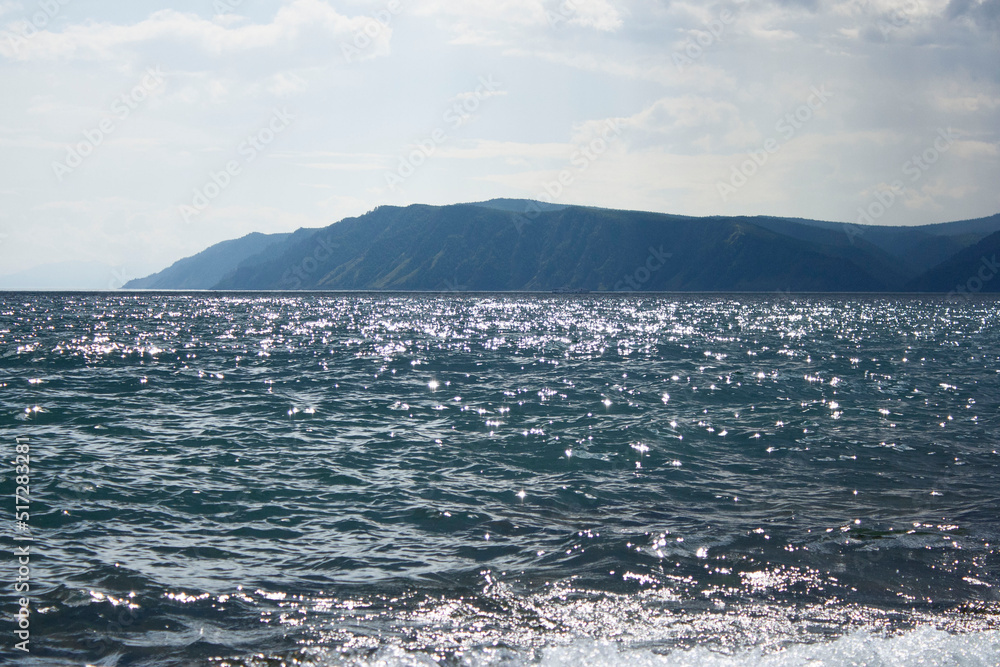 Lake Baikal. A quiet summer evening. View from the water to the west coast and the pebble shoal