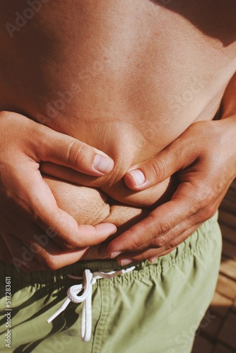 body fat and extra skin squished by hands on sunlight photo