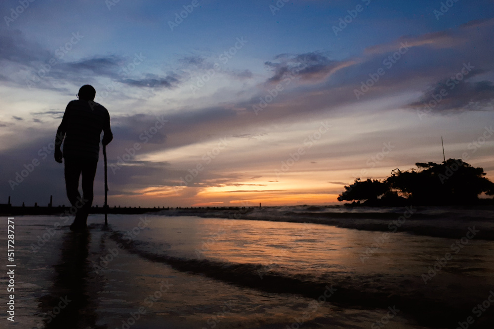 Fototapeta premium silhouette of a person walking on the beach at sunset