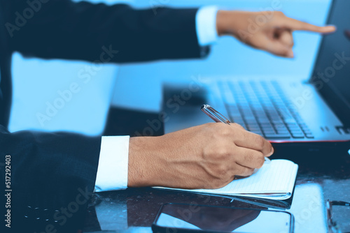 businesmen working pointing on laptop while is holding a pen writing on a notebook, Business concept