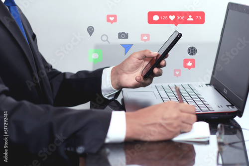 businesmen using social network on the smartphone while is working on laptop