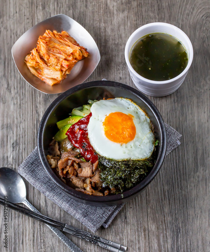 One bowl of bibimbap, korean food, serve with Seaweed soup, seaweed and Kimchi. Serve with pork and beef for add option. Food issue.