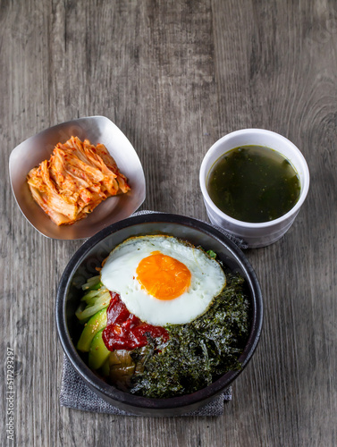One bowl of bibimbap, korean food, serve with Seaweed soup, seaweed and Kimchi. Serve with pork and beef for add option. Food issue.