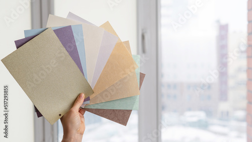 Woman holding fabric samples of roller blinds against window background.  photo