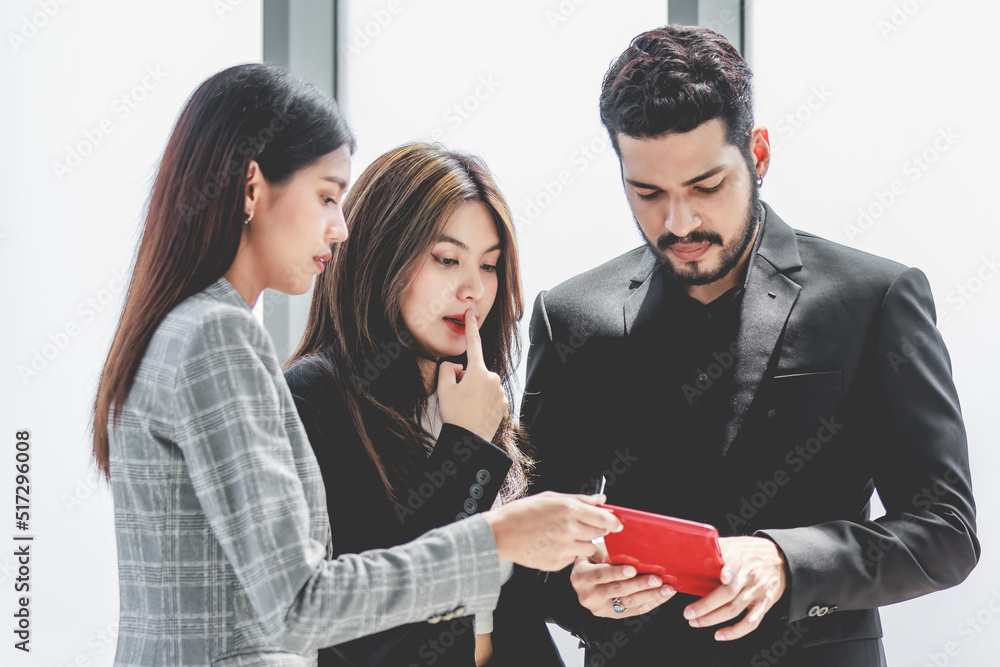 Closeup shot of two young millennial Asian doubtful female businesswomen in formal suit standing asking business solution ideas via tablet computer from Indian bearded male businessman manager mentor Closeup shot of two young millennial Asian doubtful female businesswomen in formal suit standing asking business solution ideas via tablet computer from Indian bearded male businessman manager mentor