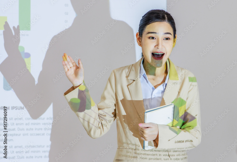Unrecognizable unknown businesswoman audience in formal suit sitting in conference meeting room holding hand up asking question while Asian female presenter presenting graph chart data on wall screen Unrecognizable unknown businesswoman audience in formal suit sitting in conference meeting room holding hand up asking question while Asian female presenter presenting graph chart data on wall screen