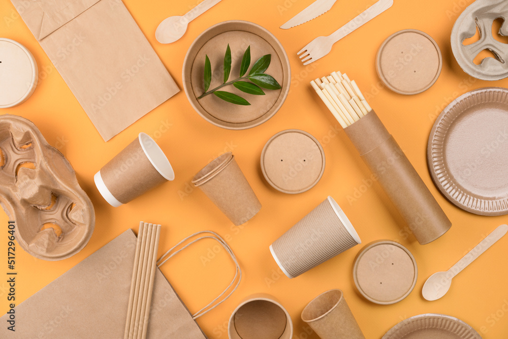 Eco-friendly tableware - kraft paper food packaging over orange background. Street food paper packaging, recyclable paperware, zero waste packaging concept. Flat lay style Eco-friendly tableware - kraft paper food packaging over orange background. Street food paper packaging, recyclable paperware, zero waste packaging concept. Flat lay style