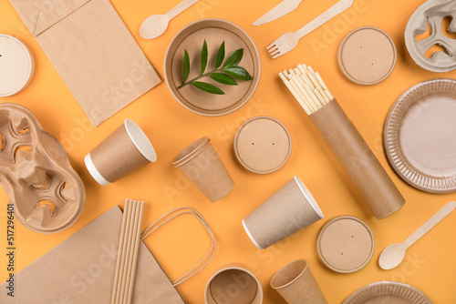 Eco-friendly tableware - kraft paper food packaging over orange background. Street food paper packaging, recyclable paperware, zero waste packaging concept. Flat lay style