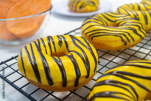 Donat ubi kuning or yellow sweet potato donuts. made from yellow sweet potato with banana flavored chocolate on top. has a soft texture
