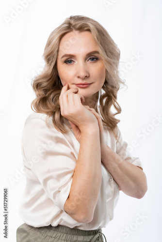 portrait of a woman. beautiful girl in a satin cream blouse on a white background. blonde with long curly hair. beauty concept