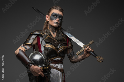 Portrait of ancient woman warrior in nordic style holding helmet and sword.