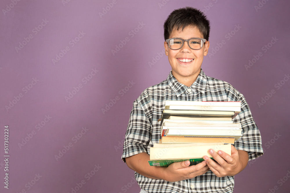 Happy smiling Latin student kid in eyeglasses holding books standing on purple background. Back to school concept. Copy space. Happy smiling Latin student kid in eyeglasses holding books standing on purple background. Back to school concept. Copy space.