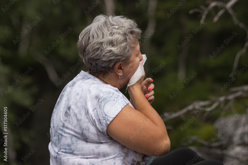 Senior woman with gray curly hair has season allergy and runny nose, sneezing. Senior woman with gray curly hair has season allergy and runny nose, sneezing.