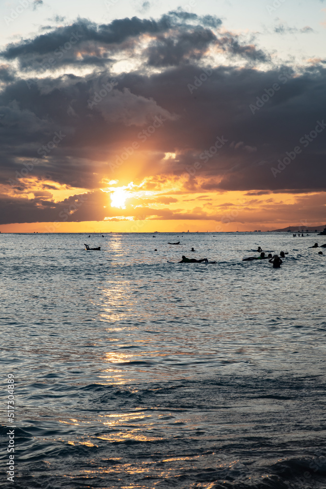 Surfers silhouette in the beach at Waikiki during sunset golden hour. Surfers silhouette in the beach at Waikiki during sunset golden hour.