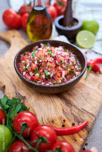 freshly made salsa dip sauce - chopped garlic, tomatoes and onion in wooden bowl