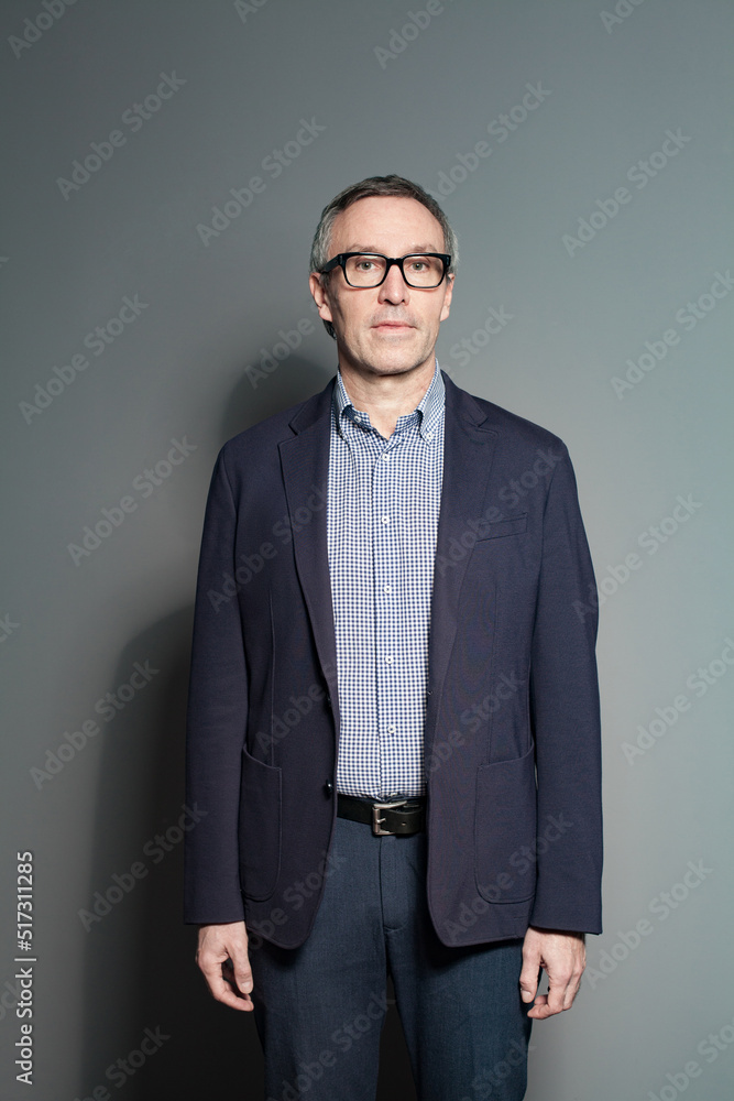 Fototapeta premium Intelligence mature businessman standing on grey background