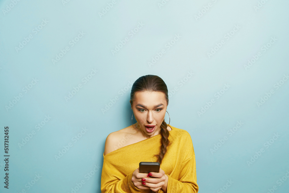 Happy surprised woman uses mobile phone, isolated over blue background. Mobile communication Happy surprised woman uses mobile phone, isolated over blue background. Mobile communication