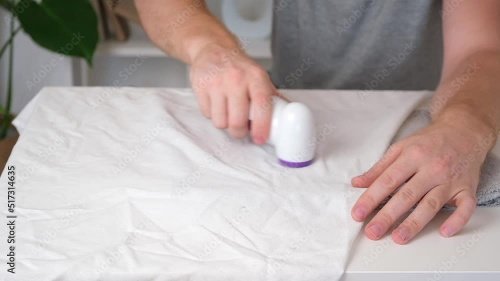 The man removes fabric pills using lint shaver. The man removes fabric pills using lint shaver.
