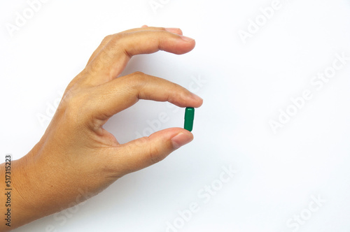 Female hand picking one pill isolated on white background.