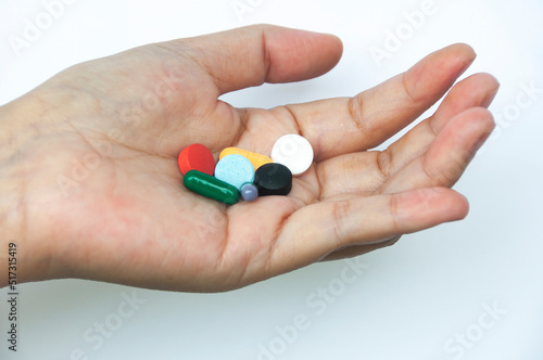 Female hand holding assorted pills isolated on white background. Copy space.