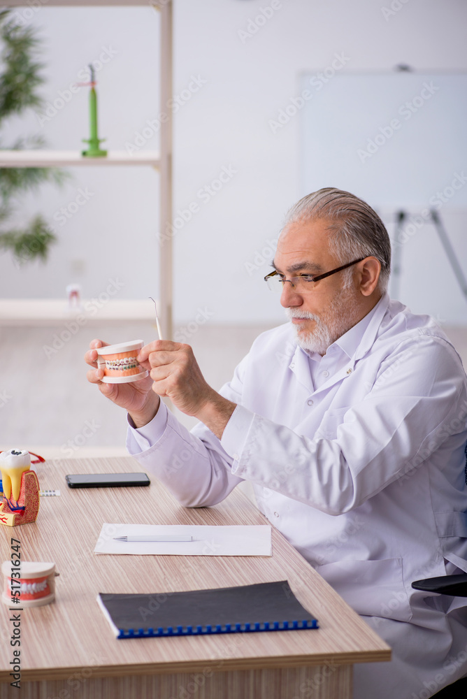 Old male dentist working in the clinic Old male dentist working in the clinic