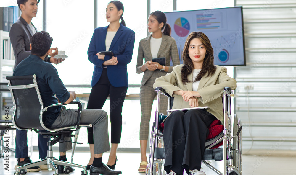 Group of millennial multinational multicultural Asian Indian businessmen and businesswomen with disabled handicapped partner sitting on wheelchair taking coffee break discussing together in office Group of millennial multinational multicultural Asian Indian businessmen and businesswomen with disabled handicapped partner sitting on wheelchair taking coffee break discussing together in office
