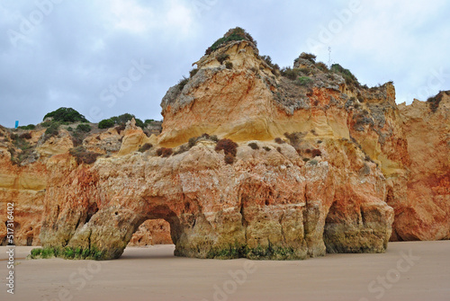Deserted Sandy Beach and Cliff with Small Cave and Cloudy Sky