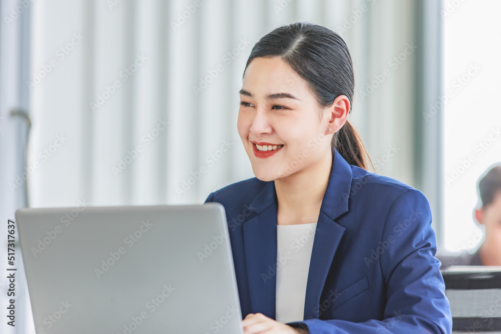 Closeup shot of millennial Asian young beautiful smart professional female businesswoman employee in formal suit sitting working on workstation desk typing laptop notebook computer in company office Closeup shot of millennial Asian young beautiful smart professional female businesswoman employee in formal suit sitting working on workstation desk typing laptop notebook computer in company office